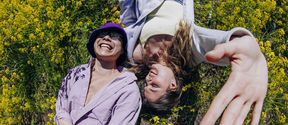 Aalto University students lying in the grass laughing.